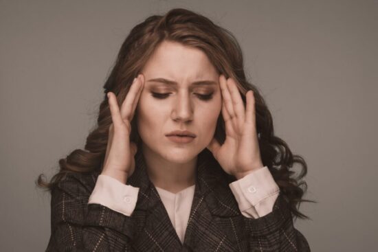 Woman holding her hands to her temple looking stressed