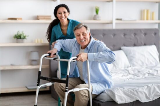 Young woman assisting elderly man trying to get up using a walker