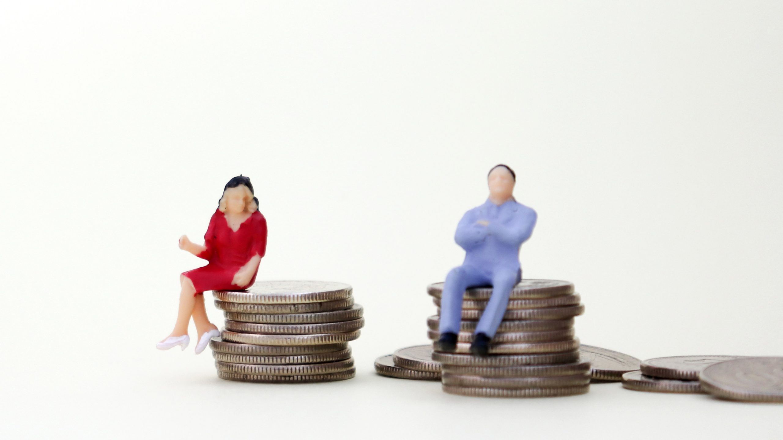 A miniature woman is sitting on a pile of coins